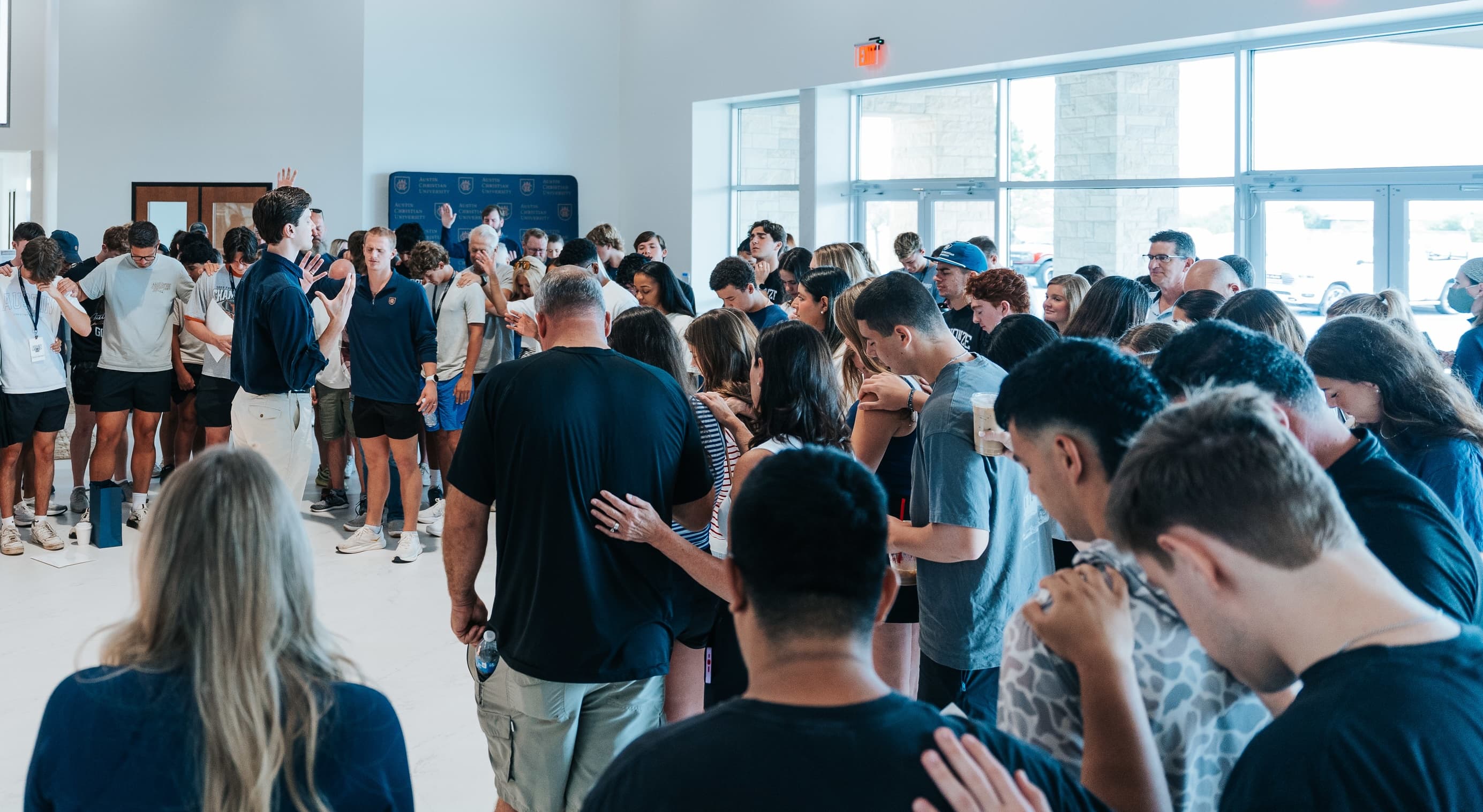 A group gathered in prayer with hands on one another's shoulders